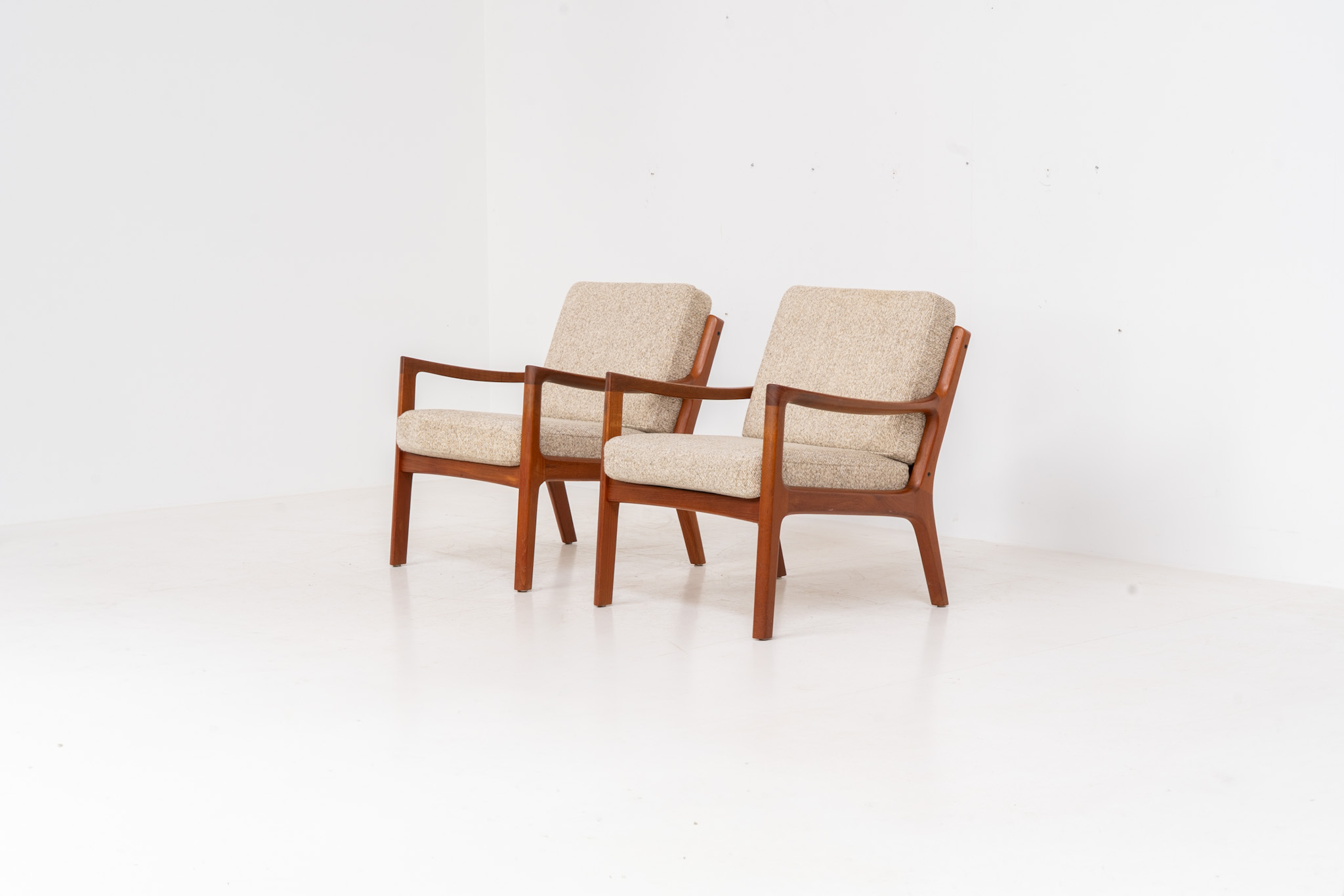 Pair of “Senator” easy chairs by Ole Wanscher for France & Son (Denmark, 1960s). An elegant pair of easy chairs and a fine example of Scandinavian Modernism. They feature a solid teak frame with a warm, natural grain, beautifully sculpted curves, and comfortable cushions upholstered in their original beige wool fabric. The chairs present beautifully and are in mint condition, fully labeled by the maker.