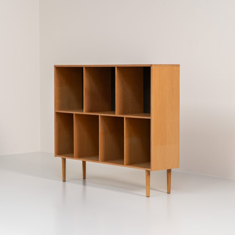 Oak bookcase by Kurt Østervig (Denmark, 1960s). A minimalistic bookcase crated in oak with vertical adjustable shelves and a contrasting dark back plate. In good condition with some discoloration on the inside.