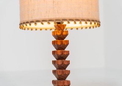 Sculptural table lamp in the manner of Charles Dudouyt (France, 1950s). This lamp offers a refined blend of beautiful textures and a highly sculptural silhouette. It has a handcrafted wooden base with lots of detail, complimented by a linnen shade. The lamp remains in splendid condition.