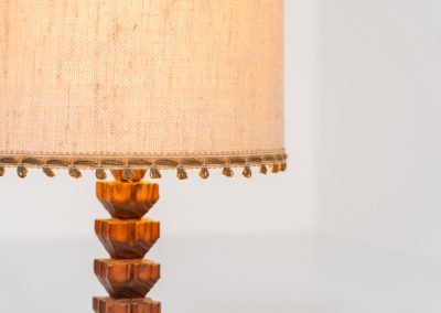 Sculptural table lamp in the manner of Charles Dudouyt (France, 1950s). This lamp offers a refined blend of beautiful textures and a highly sculptural silhouette. It has a handcrafted wooden base with lots of detail, complimented by a linnen shade. The lamp remains in splendid condition.