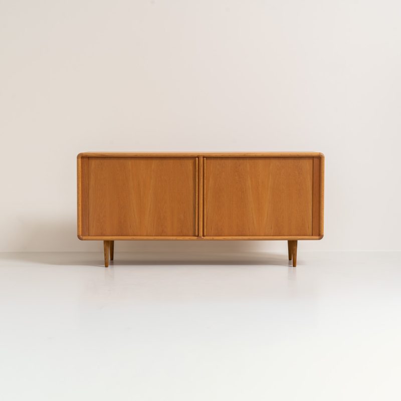 Oak sideboard with tambour doors by Kibaek Møbelfabrik (Denmark, 1960s). A beautifully crafted piece showcasing exceptional Danish design and craftsmanship. It features two tambour doors with adjustable shelves and two drawers on the inside, offering generous and flexible storage. The softly rounded edges and organic lines give the sideboard a refined, timeless character. In good condition with a mark/stain on top.