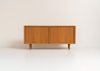 Oak sideboard with tambour doors by Kibaek Møbelfabrik (Denmark, 1960s). A beautifully crafted piece showcasing exceptional Danish design and craftsmanship. It features two tambour doors with adjustable shelves and two drawers on the inside, offering generous and flexible storage. The softly rounded edges and organic lines give the sideboard a refined, timeless character. In good condition with a mark/stain on top.