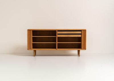 Oak sideboard with tambour doors by Kibaek Møbelfabrik (Denmark, 1960s). A beautifully crafted piece showcasing exceptional Danish design and craftsmanship. It features two tambour doors with adjustable shelves and two drawers on the inside, offering generous and flexible storage. The softly rounded edges and organic lines give the sideboard a refined, timeless character. In good condition with a mark/stain on top.