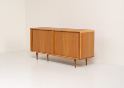 Oak sideboard with tambour doors by Kibaek Møbelfabrik (Denmark, 1960s). A beautifully crafted piece showcasing exceptional Danish design and craftsmanship. It features two tambour doors with adjustable shelves and two drawers on the inside, offering generous and flexible storage. The softly rounded edges and organic lines give the sideboard a refined, timeless character. In good condition with a mark/stain on top.