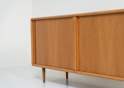 Oak sideboard with tambour doors by Kibaek Møbelfabrik (Denmark, 1960s). A beautifully crafted piece showcasing exceptional Danish design and craftsmanship. It features two tambour doors with adjustable shelves and two drawers on the inside, offering generous and flexible storage. The softly rounded edges and organic lines give the sideboard a refined, timeless character. In good condition with a mark/stain on top.