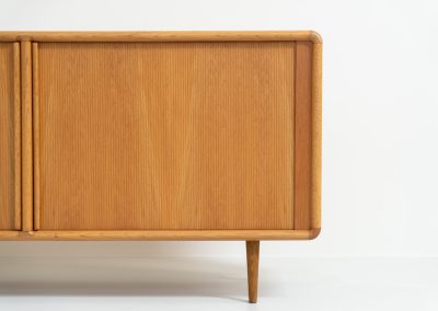Oak sideboard with tambour doors by Kibaek Møbelfabrik (Denmark, 1960s). A beautifully crafted piece showcasing exceptional Danish design and craftsmanship. It features two tambour doors with adjustable shelves and two drawers on the inside, offering generous and flexible storage. The softly rounded edges and organic lines give the sideboard a refined, timeless character. In good condition with a mark/stain on top.