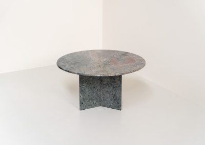 Striking dining table in solid Juparana Granite (Italy, 1970s). A beautifully sculptural piece, crafted entirely from solid Juparana Granite and distinguished by the unbelievably rich and unique grain of its tabletop. The natural variation in the stone gives the surface an almost painterly quality, making each angle of the table slightly different. Large and substantial, yet remarkably minimalistic, the table has a strong monolithic presence. The thick circular top is balanced by a sculptural three-sided pedestal base, creating a striking silhouette while keeping the overall design exceptionally clean. With its generous 130 cm diameter, the table comfortably accommodates up to six chairs. The tabletop and pedestal base are two separate pieces, making transportation and installation considerably easier despite its substantial weight. The table is in amazing condition, with no chips or structural damage.