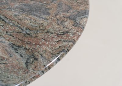 Striking dining table in solid Juparana Granite (Italy, 1970s). A beautifully sculptural piece, crafted entirely from solid Juparana Granite and distinguished by the unbelievably rich and unique grain of its tabletop. The natural variation in the stone gives the surface an almost painterly quality, making each angle of the table slightly different. Large and substantial, yet remarkably minimalistic, the table has a strong monolithic presence. The thick circular top is balanced by a sculptural three-sided pedestal base, creating a striking silhouette while keeping the overall design exceptionally clean. With its generous 130 cm diameter, the table comfortably accommodates up to six chairs. The tabletop and pedestal base are two separate pieces, making transportation and installation considerably easier despite its substantial weight. The table is in amazing condition, with no chips or structural damage.