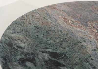 Striking dining table in solid Juparana Granite (Italy, 1970s). A beautifully sculptural piece, crafted entirely from solid Juparana Granite and distinguished by the unbelievably rich and unique grain of its tabletop. The natural variation in the stone gives the surface an almost painterly quality, making each angle of the table slightly different. Large and substantial, yet remarkably minimalistic, the table has a strong monolithic presence. The thick circular top is balanced by a sculptural three-sided pedestal base, creating a striking silhouette while keeping the overall design exceptionally clean. With its generous 130 cm diameter, the table comfortably accommodates up to six chairs. The tabletop and pedestal base are two separate pieces, making transportation and installation considerably easier despite its substantial weight. The table is in amazing condition, with no chips or structural damage.