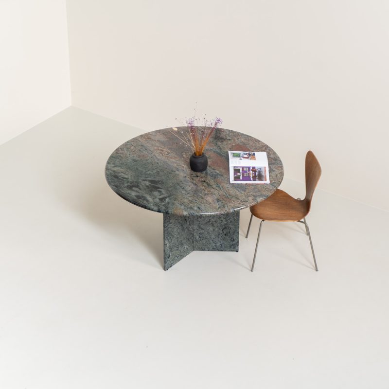 Striking dining table in solid Juparana Granite (Italy, 1970s). A beautifully sculptural piece, crafted entirely from solid Juparana Granite and distinguished by the unbelievably rich and unique grain of its tabletop. The natural variation in the stone gives the surface an almost painterly quality, making each angle of the table slightly different. Large and substantial, yet remarkably minimalistic, the table has a strong monolithic presence. The thick circular top is balanced by a sculptural three-sided pedestal base, creating a striking silhouette while keeping the overall design exceptionally clean. With its generous 130 cm diameter, the table comfortably accommodates up to six chairs. The tabletop and pedestal base are two separate pieces, making transportation and installation considerably easier despite its substantial weight. The table is in amazing condition, with no chips or structural damage.