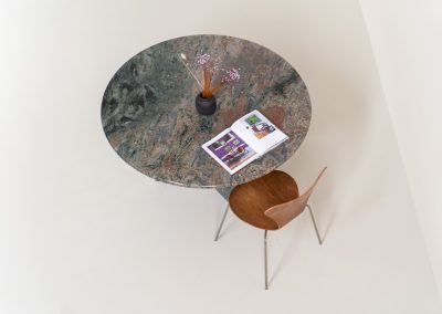 Striking dining table in solid Juparana Granite (Italy, 1970s). A beautifully sculptural piece, crafted entirely from solid Juparana Granite and distinguished by the unbelievably rich and unique grain of its tabletop. The natural variation in the stone gives the surface an almost painterly quality, making each angle of the table slightly different. Large and substantial, yet remarkably minimalistic, the table has a strong monolithic presence. The thick circular top is balanced by a sculptural three-sided pedestal base, creating a striking silhouette while keeping the overall design exceptionally clean. With its generous 130 cm diameter, the table comfortably accommodates up to six chairs. The tabletop and pedestal base are two separate pieces, making transportation and installation considerably easier despite its substantial weight. The table is in amazing condition, with no chips or structural damage.
