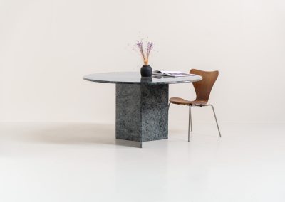 Striking dining table in solid Juparana Granite (Italy, 1970s). A beautifully sculptural piece, crafted entirely from solid Juparana Granite and distinguished by the unbelievably rich and unique grain of its tabletop. The natural variation in the stone gives the surface an almost painterly quality, making each angle of the table slightly different. Large and substantial, yet remarkably minimalistic, the table has a strong monolithic presence. The thick circular top is balanced by a sculptural three-sided pedestal base, creating a striking silhouette while keeping the overall design exceptionally clean. With its generous 130 cm diameter, the table comfortably accommodates up to six chairs. The tabletop and pedestal base are two separate pieces, making transportation and installation considerably easier despite its substantial weight. The table is in amazing condition, with no chips or structural damage.