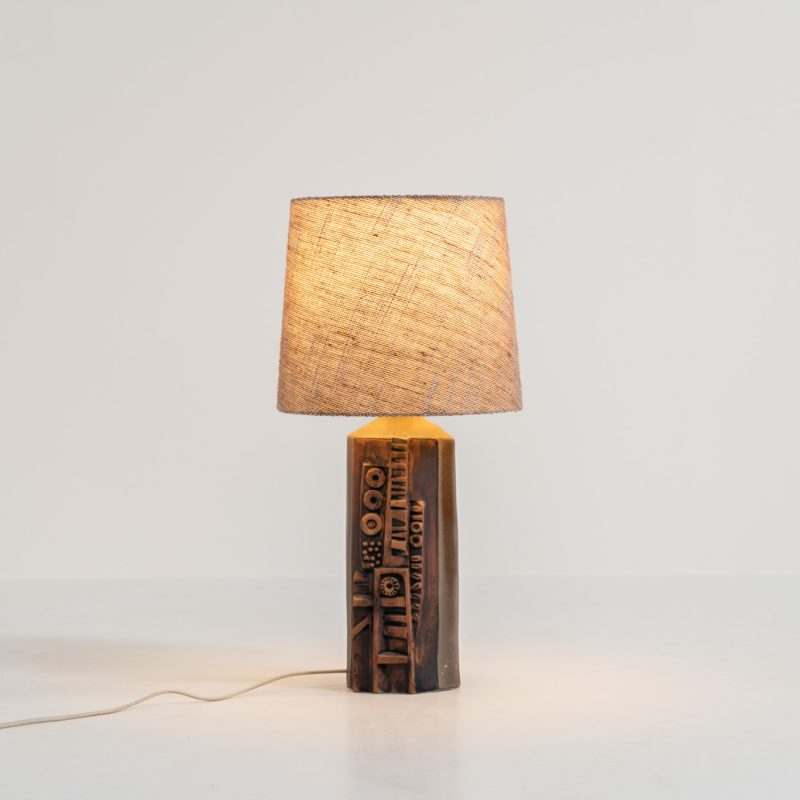 Sculptural “Kennegie” ceramic lamp by Peter Ellery for Tremaen (UK, 1960s). This lamp offers a refined blend of beautiful textures and timeless design. It has a handcrafted ceramic base with earthy colors and graphic engravings. The lamp remains in splendid condition.