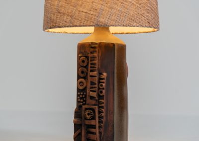 Sculptural “Kennegie” ceramic lamp by Peter Ellery for Tremaen (UK, 1960s). This lamp offers a refined blend of beautiful textures and timeless design. It has a handcrafted ceramic base with earthy colors and graphic engravings. The lamp remains in splendid condition.