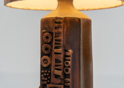 Sculptural “Kennegie” ceramic lamp by Peter Ellery for Tremaen (UK, 1960s). This lamp offers a refined blend of beautiful textures and timeless design. It has a handcrafted ceramic base with earthy colors and graphic engravings. The lamp remains in splendid condition.