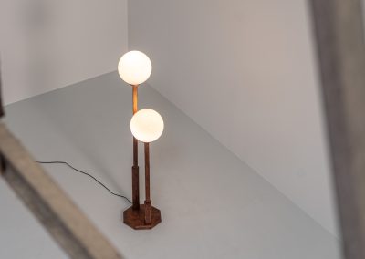 Wood & opal glass floor lamp, 1970s. Vintage floor lamp featuring a sculptural, geometric wooden base with two slender stems at different heights, each topped with a spherical opaline glass shade. The warm-toned wood and softly diffused light create a beautiful balance between architectural form and understated elegance. A distinctive vintage piece that works as both a functional light source and a sculptural accent in a contemporary or mid-century inspired interior. The lamp is in very good vintage condition overall, with a subtle historic repair to the wood near the base of one glass support.