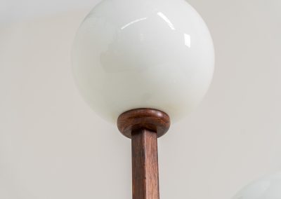 Wood & opal glass floor lamp, 1970s. Vintage floor lamp featuring a sculptural, geometric wooden base with two slender stems at different heights, each topped with a spherical opaline glass shade. The warm-toned wood and softly diffused light create a beautiful balance between architectural form and understated elegance. A distinctive vintage piece that works as both a functional light source and a sculptural accent in a contemporary or mid-century inspired interior. The lamp is in very good vintage condition overall, with a subtle historic repair to the wood near the base of one glass support.