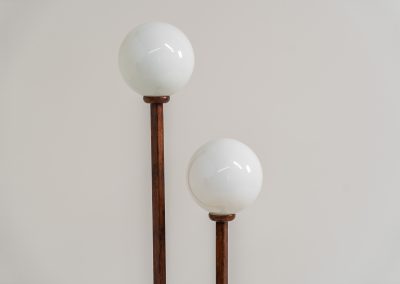 Wood & opal glass floor lamp, 1970s. Vintage floor lamp featuring a sculptural, geometric wooden base with two slender stems at different heights, each topped with a spherical opaline glass shade. The warm-toned wood and softly diffused light create a beautiful balance between architectural form and understated elegance. A distinctive vintage piece that works as both a functional light source and a sculptural accent in a contemporary or mid-century inspired interior. The lamp is in very good vintage condition overall, with a subtle historic repair to the wood near the base of one glass support.